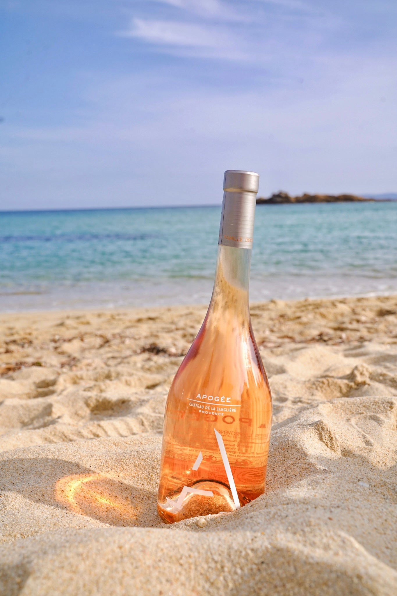 Bouteille de rosé de la Sanglière posée sur le sable face à la mer Méditerranée.